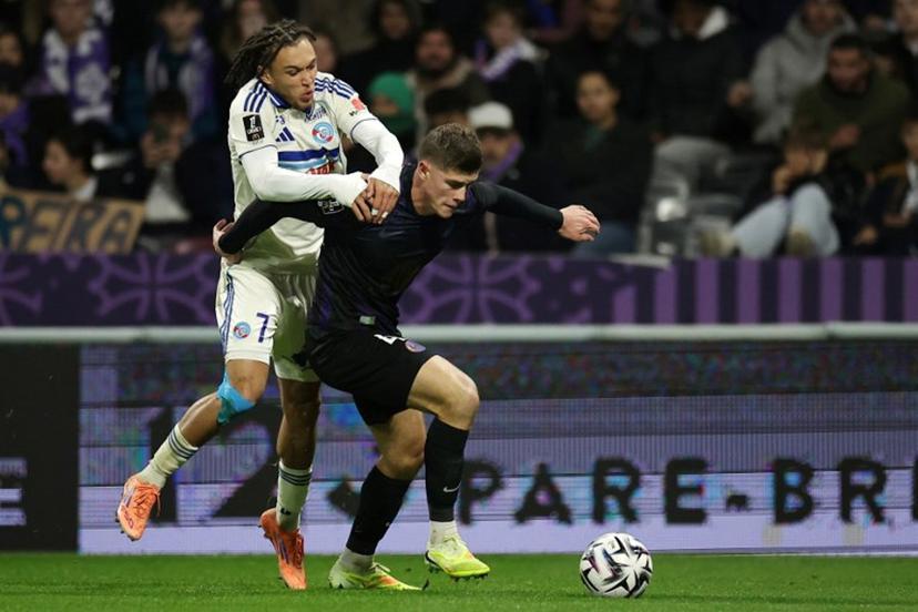 Strasbourg's Belgian midfielder #07 Diego Moreira (L) fights for the ball with Toulouse's English defender #04 Charlie Cresswell (R) during the French L1 football match between Toulouse FC and RC Strasbourg Alsace at the TFC Stadium in Toulouse, southwestern France, on December 6, 2025.  Valentine CHAPUIS / AFP