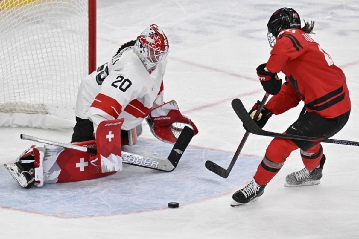 Canada's forward #40 Blayre Turnbull (R) controls the puck in front of Switzerland's goalkeeper #20 Andrea Braendli during the women's play-off semi-final ice hockey match between Canada and Switzerland at the Milano Santagiulia Ice Hockey Arena during the Milano Cortina 2026 Winter Olympic Games in Milan, on February 16, 2026.  Alexander NEMENOV / AFP