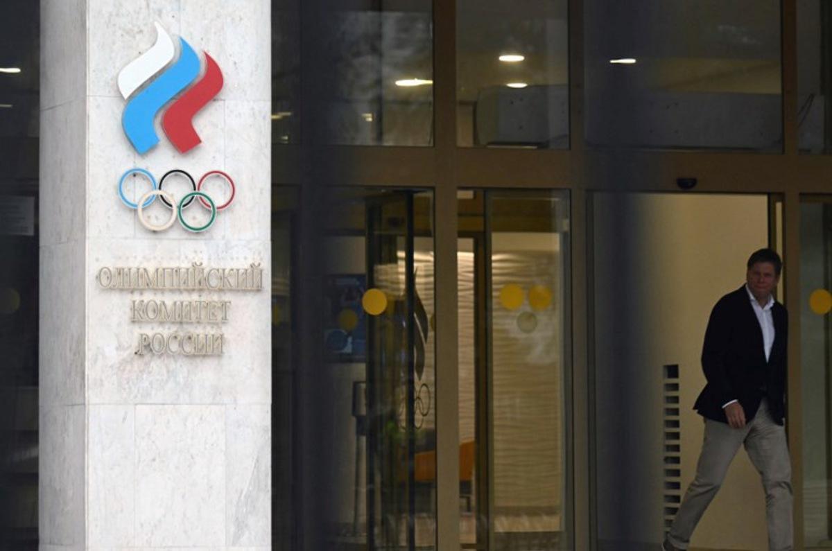 A man walks past the logo of the Russian Olympic Committee (ROC) as he leaves the office in Moscow on October 15, 2024. The head of Russia's Olympic Committee announced his resignation on October 15, 2024, a surprise move that comes as Moscow faces isolation from international sport over its Ukraine offensive. Former fencer, Stanislav Pozdnyakov, a five-time Olympic medallist, said in his resignation letter there were "timely" reasons why Russian sport needed a new leader, without going into detail. Natalia KOLESNIKOVA / AFP