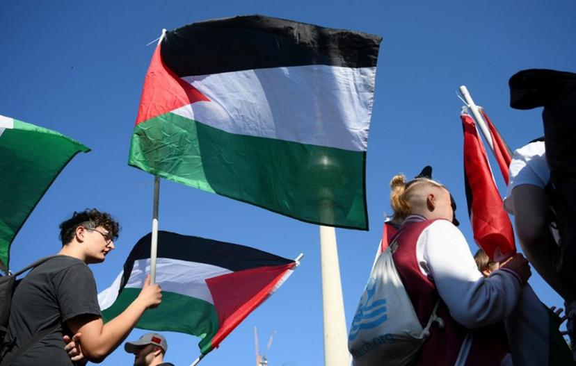 A participant displays a Palestinian flag during a demonstration under the motto 'Draw the red line with us: Together for Gaza!' in Berlin on September 27, 2025.   RALF HIRSCHBERGER / AFP