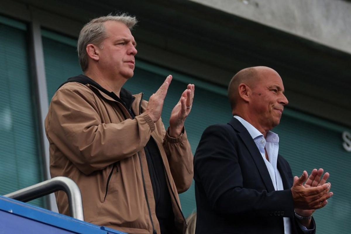 Chelsea's US owner Todd Boehly (L) applauds for former chairman Ken Bates and former player Bobby Tambling after a moment of silence before the start of the English Premier League football match between Chelsea and Brighton and Hove Albion at Stamford Bridge in London on August 30, 2026.  Adrian Dennis / AFP
