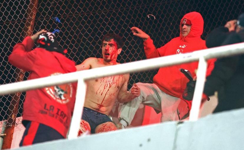 (FILES) A fan of Universidad de Chile bleeds while being hit by fans of Independiente during the interruption of the Copa Sudamericana round of 16 second leg football match between Argentina's Independiente and Chile's Universidad de Chile at the Libertadores de America stadium in Avellaneda, Buenos Aires province, Argentina, on August 20, 2025. South American football's governing body Conmebol on September 4, 2025, disqualified Argentina's Independiente from the 2025 Copa Sudamericana club competition over a bloody brawl during a game against Universidad de Chile last month. The Chilean team, meanwhile, will advance to the quarter-finals. Both teams will have to play their next 14 matches in Conmebol tournaments without their fans—seven at home and seven away—and received hefty fines, among other sanctions, according to the ruling known to AFP. ALEJANDRO PAGNI / AFP