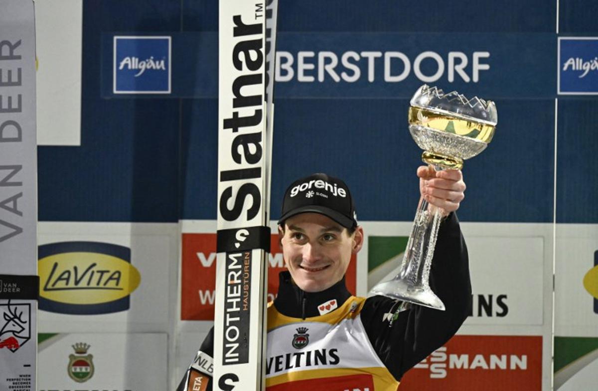 Winner, Slovenia's Domen Prevc, celebrates on the podium with his trophy after the second jump of the Men's Individual Large Hill HS137 event of the FIS Ski Jumping World Cup, the first leg of the Four Hills Tournament, in Oberstdorf, southern Germany on December 29, 2025.  PHILIPP GUELLAND / AFP