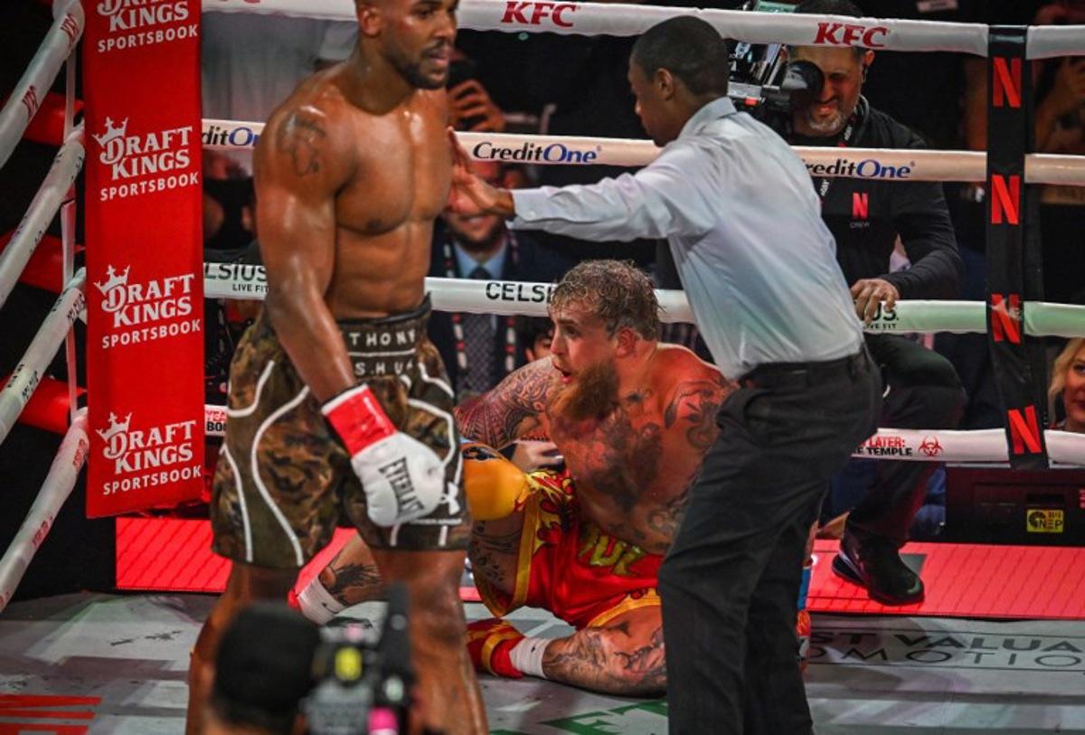 Referee Christopher Young counts over US boxer and influencer Jake Paul as he sits on the floor during his fight against British boxer Anthony Joshua (L) in a non-title heavyweight bout at the Kaseya Center in Miami, Florida, on December 19, 2025.  Giorgio VIERA / AFP