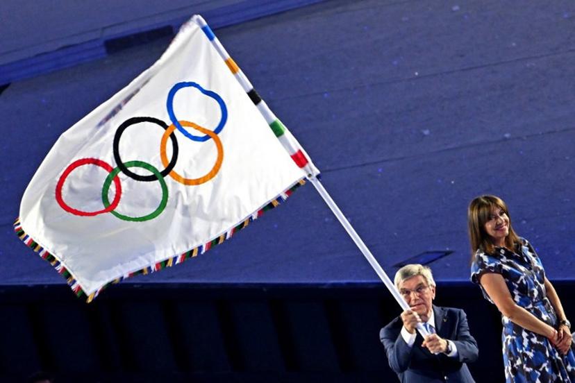 International Olympic Committe (IOC) President Thomas Bach (L) waves the Olympic flag next to Paris' Mayor Anne Hidlago during the handing of the flag as part of the closing ceremony of the Paris 2024 Olympic Games at the Stade de France, in Saint-Denis, in the outskirts of Paris, on August 11, 2024.  Miguel MEDINA / AFP