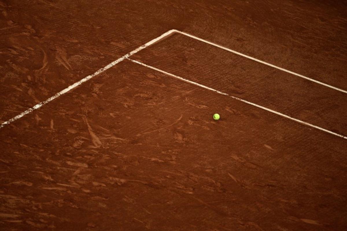 An official Roland-Garros tennis ball sits on the clay on day 1 of the French Open tennis tournament on Court Suzanne-Lenglen at the Roland-Garros Complex in Paris on May 24, 2026.  JULIEN DE ROSA / AFP