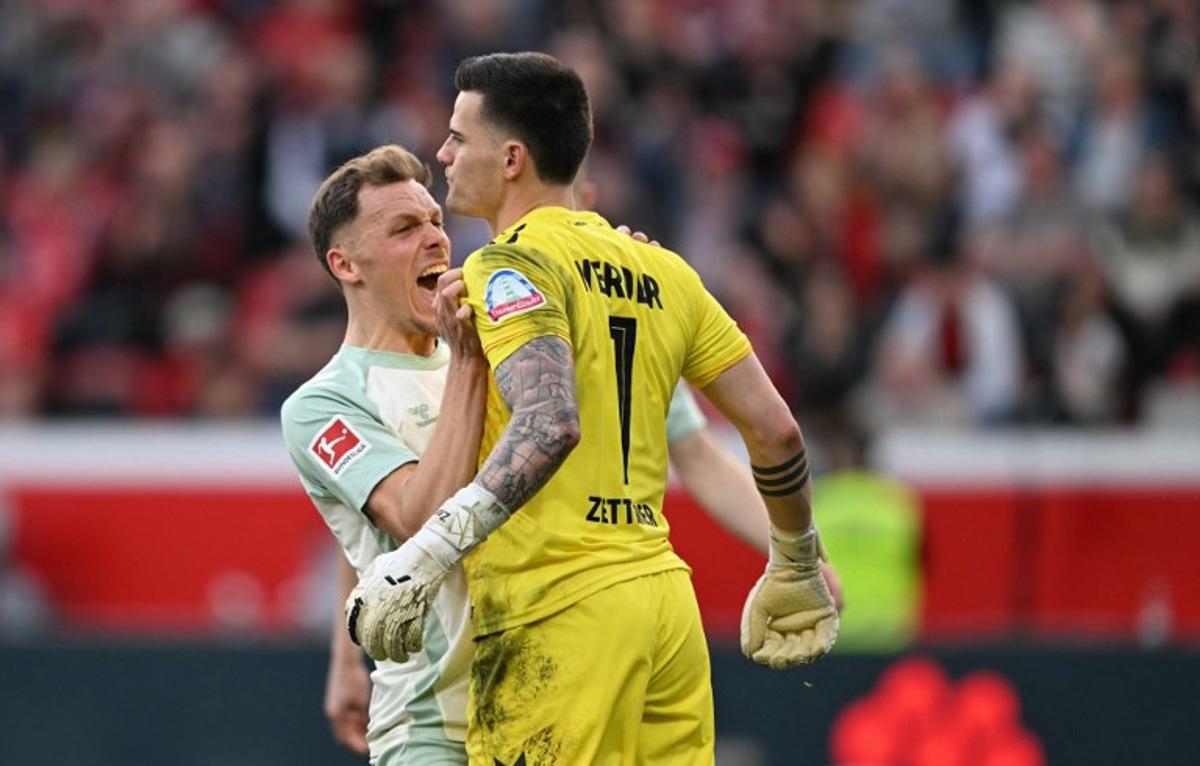 Bremen's Belgian midfielder #14 Senne Lynen (L) and Bremen's German goalkeeper #01 Michael Zetterer react during the German first division Bundesliga football match between Bayer Leverkusen and Werder Bremen in Leverkusen, western Germany, on March 8, 2025.  INA FASSBENDER / AFP