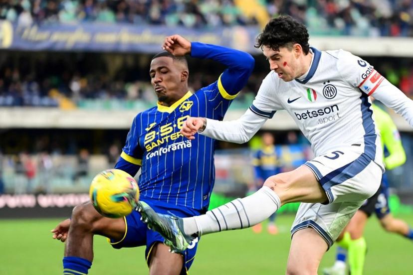 Inter Milan's Italian defender #95 Alessandro Bastoni  shoots past Hellas Verona's Belgian midfielder #38 Jackson Tchatchoua during the Italian Serie A football match between Hellas Verona and Inter Milan at Marcantonio Bentegodi Stadium, in Verona on November 23, 2024. This weekend, players in Serie A  are sporting a red mark on their cheeks as part of a campaign challenging violence against women, participating in the campaign Un Rosso Alla Violenza - A red card to violence. Piero CRUCIATTI / AFP