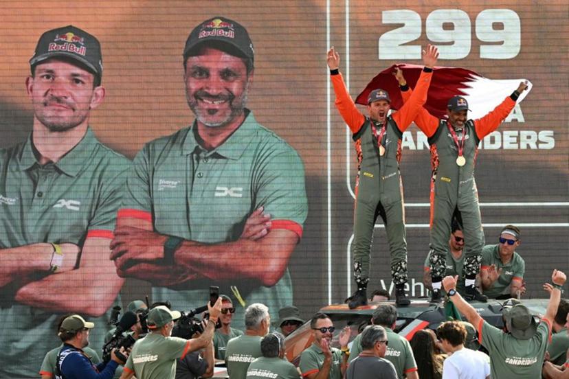 The Dacia Sandriders' Qatari driver Nasser al-Attiyah (R) and Belgian copilot Fabian Lurquin celebrate on the podium after winning the 48th edition of the Dakar Rally 2026 in Yanbu, Saudi Arabia, on January 17, 2026. Qatar's Nasser Al-Attiyah secured his sixth Dakar Rally car title in Saudi Arabia. Giuseppe CACACE / AFP