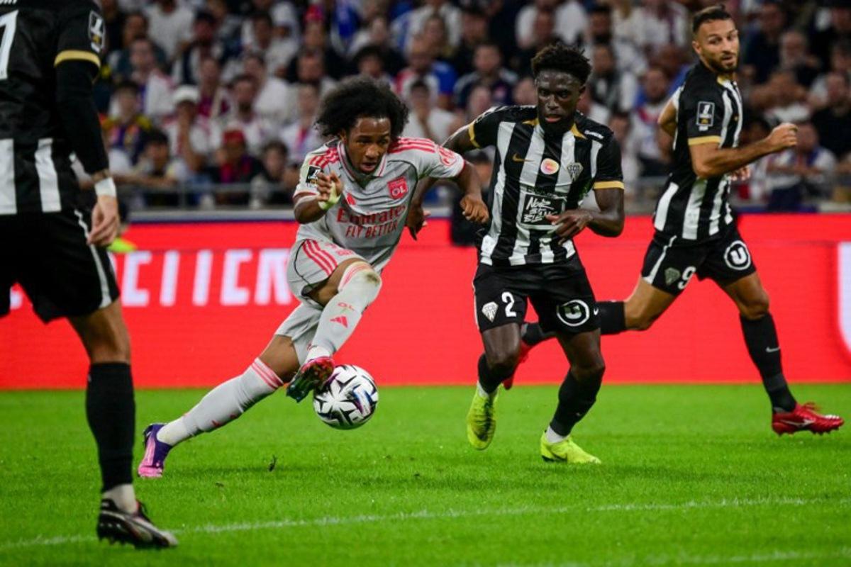 Lyon's Belgian forward #11 Malick Fofana (C-L) fights for the ball with Angers' Haitian defender #02 Carlens Arcus (C-R) during the French L1 football match between Olympique Lyonnais (OL) and SCO Angers at the Groupama Stadium in Decines-Charpieu, near Lyon, central-eastern France on September 19, 2025.  OLIVIER CHASSIGNOLE / AFP