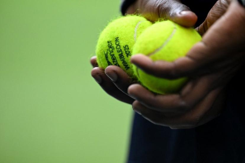 A ball boy holds tennis balls on Centre Court on the tenth day of the 2025 Wimbledon Championships at The All England Lawn Tennis and Croquet Club in Wimbledon, southwest London, on July 9, 2025.  Kirill KUDRYAVTSEV / AFP