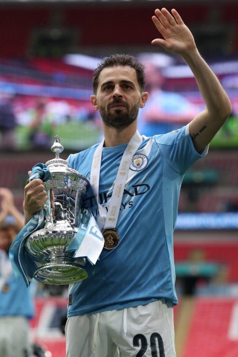 Manchester City's Portuguese midfielder #20 Bernardo Silva poses with the trophy on the pitch after the English FA Cup final football match between Chelsea and Manchester City at Wembley stadium in London, on May 16, 2026. Manchester City won the game 1-0. The third FA Cup success of Guardiola's reign ended City's run of two successive defeats in the final. Adrian Dennis / AFP