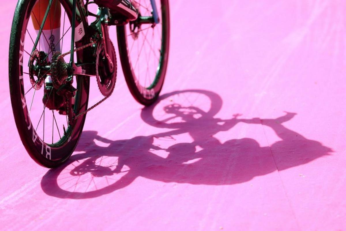 A photograph shows the shadows of a rider arriving to attend the signature ceremony ahead of the start of the stage 1 of the Giro d'Italia 2024 cycling race, 140 km between Venaria Reale and Torino on May 4, 2024. The 107th edition of the Giro d'Italia, with a total of 3400,8 km, departs from Veneria Reale near Turin on May 4, 2024 and will finish in Rome on May 26, 2024. Luca Bettini / AFP