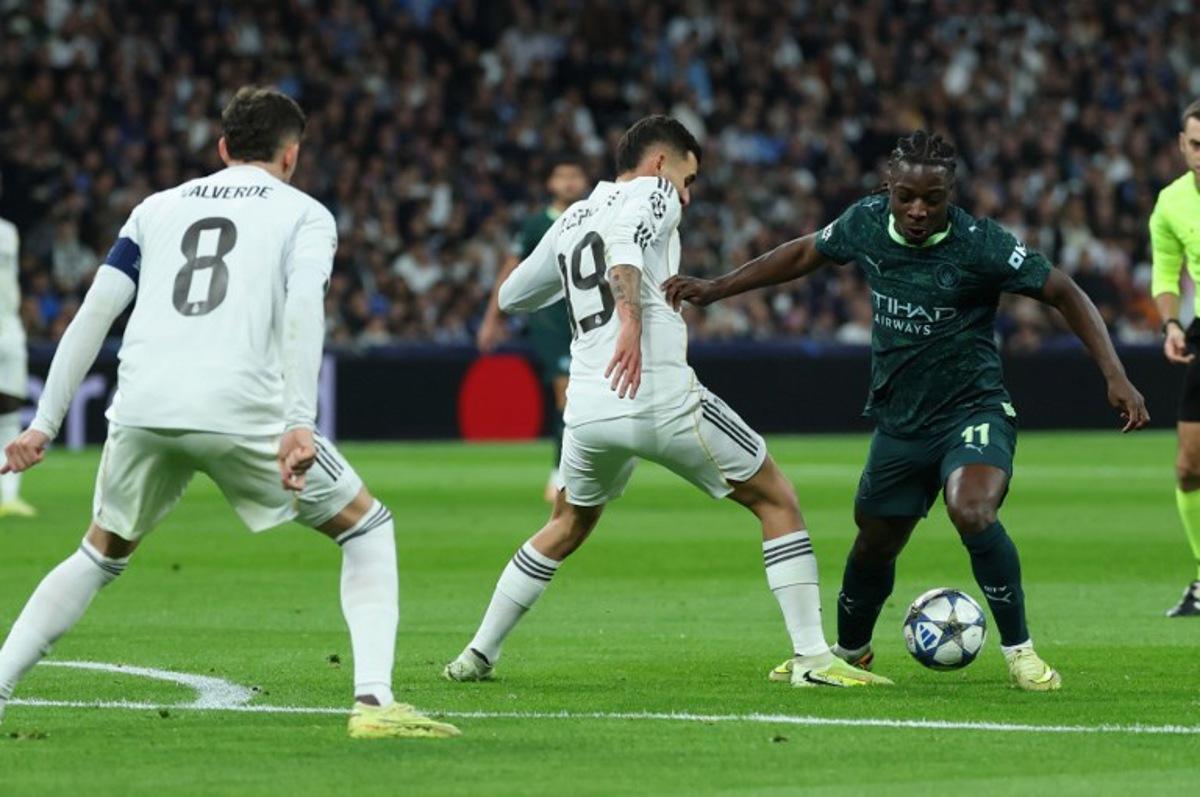 Manchester City's Belgian midfielder #11 Jeremy Doku (R) vies for the ball with Real Madrid's Spanish midfielder #19 Dani Ceballos during the UEFA Champions League league phase day 6 football match between Real Madrid CF and Manchester City at Santiago Bernabeu Stadium in Madrid on December 10, 2025. Thomas COEX / AFP