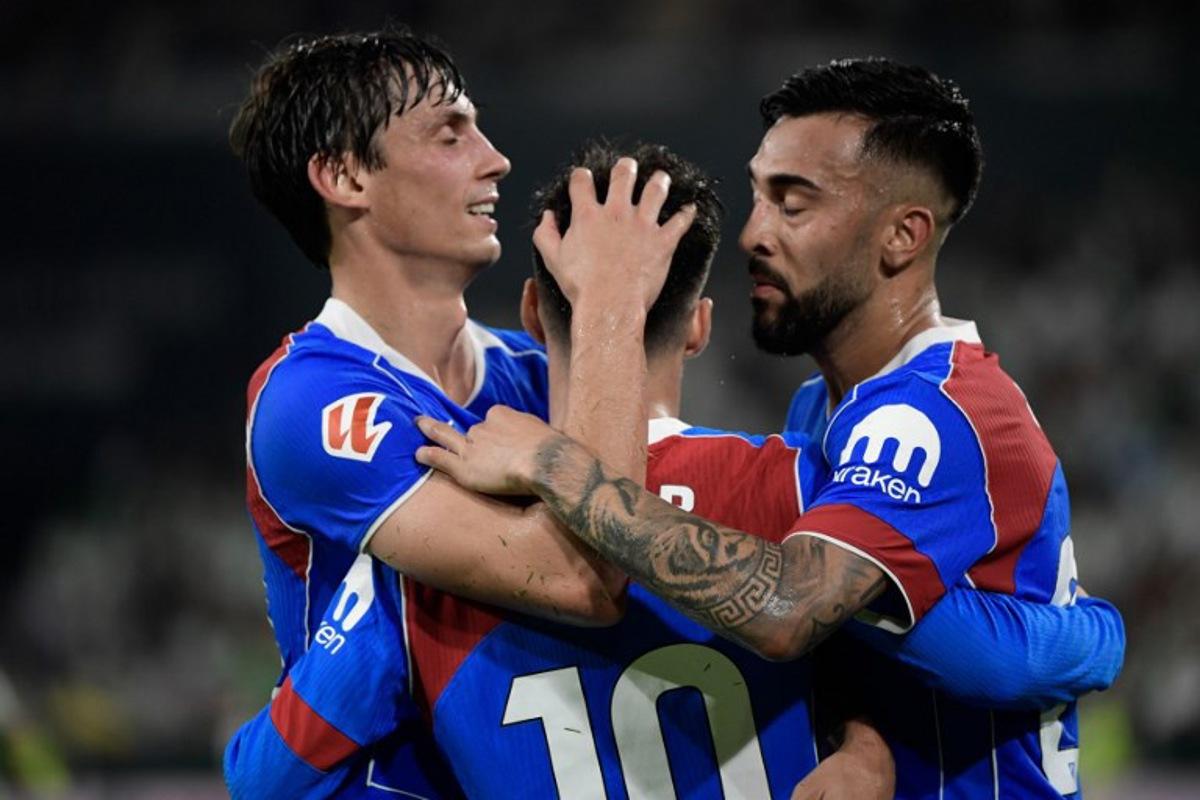 Atletico Madrid's Spanish forward #10 Alex Baena (C) celebrates with teammates after scoring their second goal during the Spanish league football match between Real Betis and Club Atletico de Madrid at the Cartuja Stadium in Seville on October 27, 2025. CRISTINA QUICLER / AFP