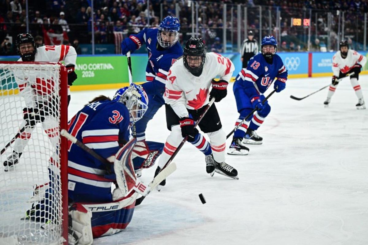 Canada's #24 Natalie Spooner (C) fights for the puck with USA's #05 Megan Keller (2nd L) and USA's #31 Aerin Frankel (L) during the women's gold medal ice hockey match between USA and Canada at the Milano Santagiulia Ice Hockey Arena during the Milano Cortina 2026 Winter Olympic Games in Milan, on February 19, 2026. JULIEN DE ROSA / AFP