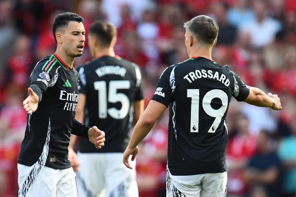 Arsenal's Brazilian midfielder #11 Gabriel Martinelli (L) celebrates with Arsenal's Belgian midfielder #19 Leandro Trossard (R) after scoring their first goal during the English Premier League football match between Liverpool and Arsenal at Anfield in Liverpool, north west England on May 11, 2025. PETER POWELL / AFP