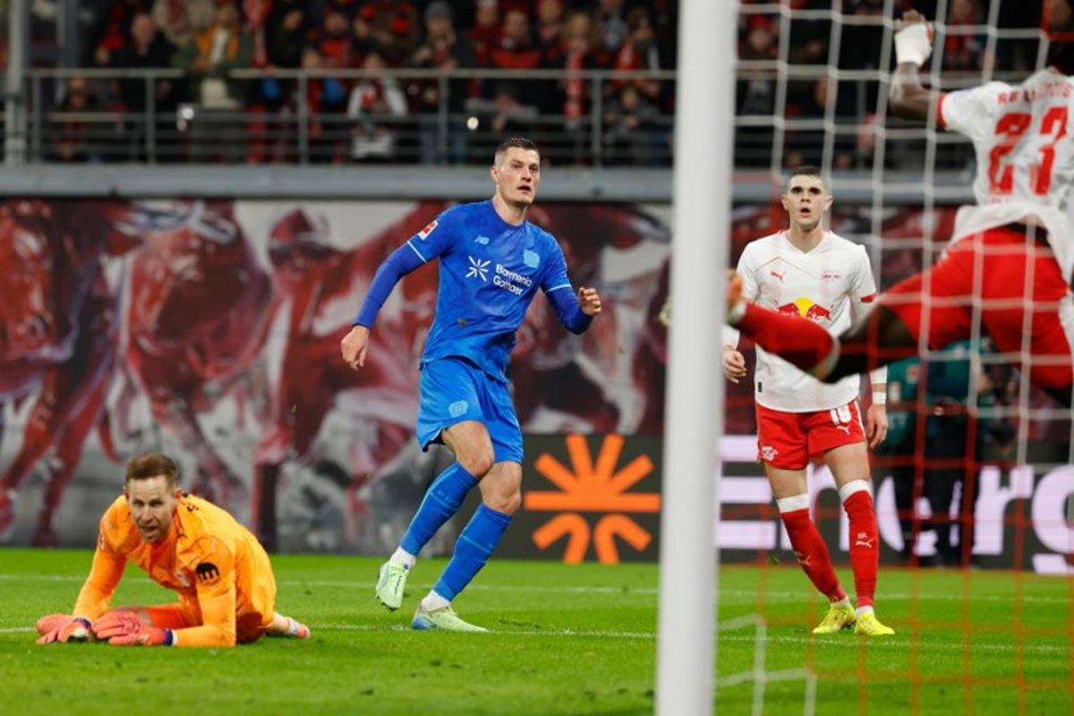 Bayer Leverkusen's Czech forward #14 Patrik Schick (C) scores the 1-2 goal past Leipzig's Hungarian goalkeeper #01 Peter Gulacsi (L) during the German first division Bundesliga football match between RB Leipzig and Bayer 04 Leverkusen in Leipzig, eastern Germany, on December 20, 2025. Odd ANDERSEN / AFP