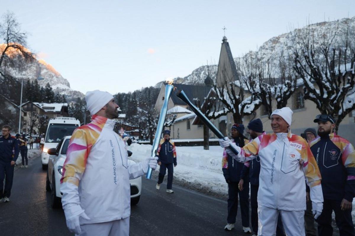Torchbearers take part in the relay of the Olympic flame in Cortina d'Ampezzo on January 26, 2026. Odd ANDERSEN / AFP