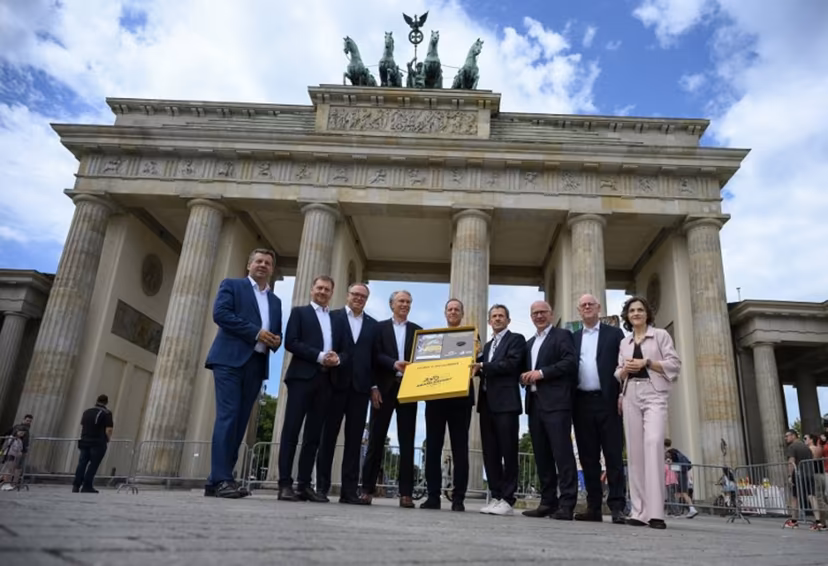 Tour de France director Christian Prudhomme (C) poses for a group photo with the bid for the 2029 Tour de France (TDF) departure in Berlin, in front of landmark Brandenburg Gate with German Cycling Association Bernd Dankowski (4thL) and ASO (Amaury Sport Organisation)'s CEO Yann Le Moenner (4theR), and (L-R) Saxony-Anhalt's State Premier Sven Schulze, Saxony's State Premier Michael Kretschmer, Thuringia's State Premier Mario Voigt, Berlin's mayor Kai Wegner, former President of the German Cycling Federation Rudolf Scharping and the government's commissionner for Eastern Germany Elisabeth Kaiser, in Berlin, on July 29, 2026. RALF HIRSCHBERGER / AFP