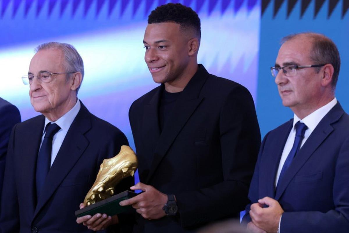 Real Madrid's French forward Kylian Mbappe (C) smiles beside President of Real Madrid Florentino Perez (L), after receiving the 2024-25 European Golden Shoe award honoring the year's leading goalscorer during a ceremony at Santiago Bernabeu Stadium in Madrid on October 31, 2024.  Oscar DEL POZO / AFP