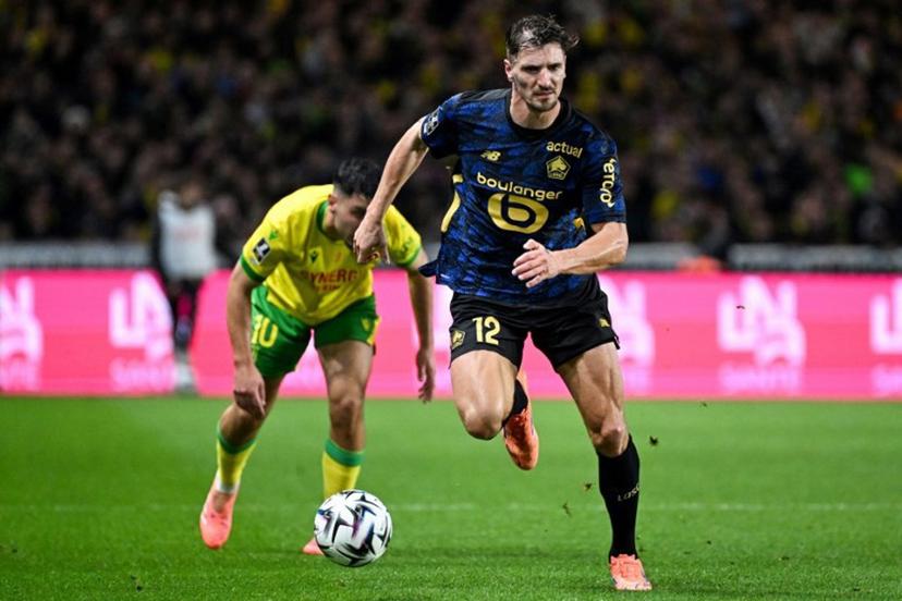 Lille's Belgian defender #12 Thomas Meunier (front) controls the ball past Nantes' French forward #10 Matthis Abline (rear L) during the French L1 football match between FC Nantes and Lille LOSC at the Stade de la Beaujoire-Louis Fonteneau in Nantes, western France, on October 19, 2025. Sebastien Salom-Gomis / AFP