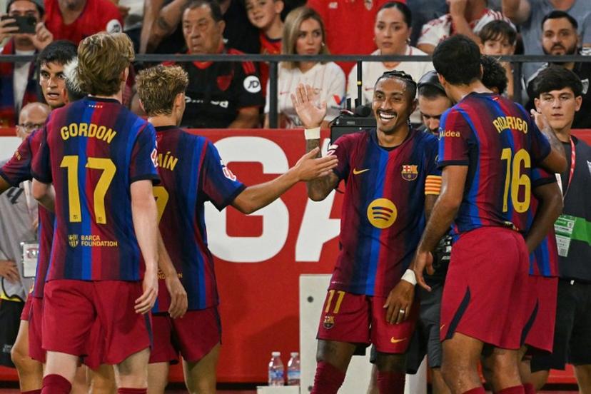 Barcelona's Brazilian forward #11 Raphinha (C) celebrates with teammates after scoring his team's third goal during the Spanish league football match between Sevilla FC and FC Barcelona at the Ramon Sanchez Pizjuan stadium in Seville on September 19, 2026. JORGE GUERRERO / AFP