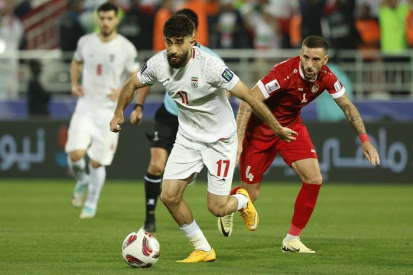 Iran's midfielder #17 Ali Gholizadeh runs with the ball past Syria's midfielder #04 Ezequiel Ham during the Qatar 2023 AFC Asian Cup football match between Iran and Syria at the Abdullah bin Khalifa Stadium in Doha on January 31, 2024. KARIM JAAFAR / AFP