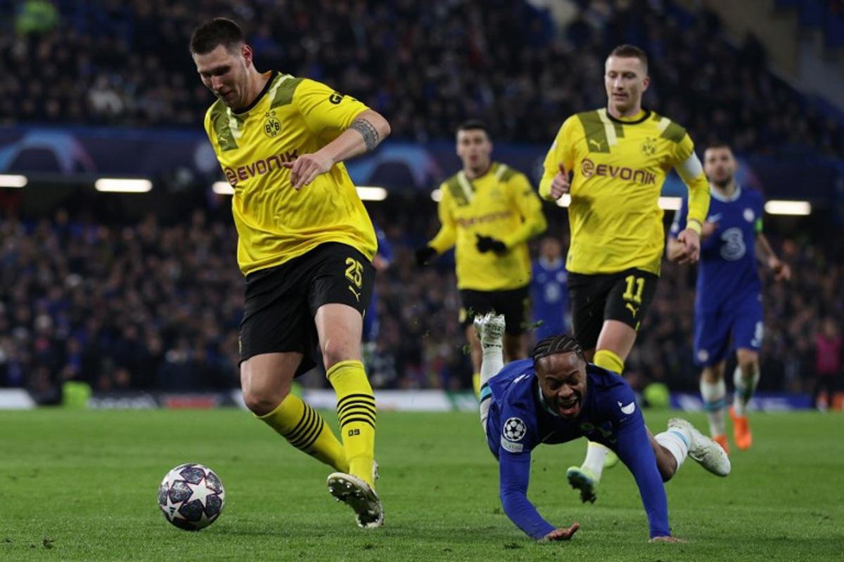 Chelsea's English midfielder Raheem Sterling (C) falsl to the ground after chalenging Dortmund's German defender Niklas Sule (L) during the UEFA Champions League round of 16 second-leg football match between Chelsea and Borrusia Dortmund at Stamford Bridge in London on March 7, 2023. ADRIAN DENNIS / AFP