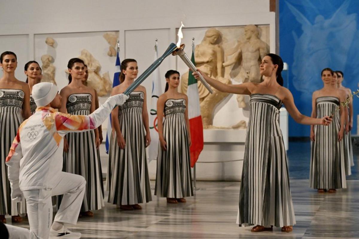 Greek actress Mary Mina (R), playing the role of the High Priestess, takes part in the flame lighting ceremony of the Olympic flame, for the Olympic Winter Games Milano Cortina 2026, at the Museum of ancient Olympia, in Olympia on November 26, 2025. Aris MESSINIS / AFP