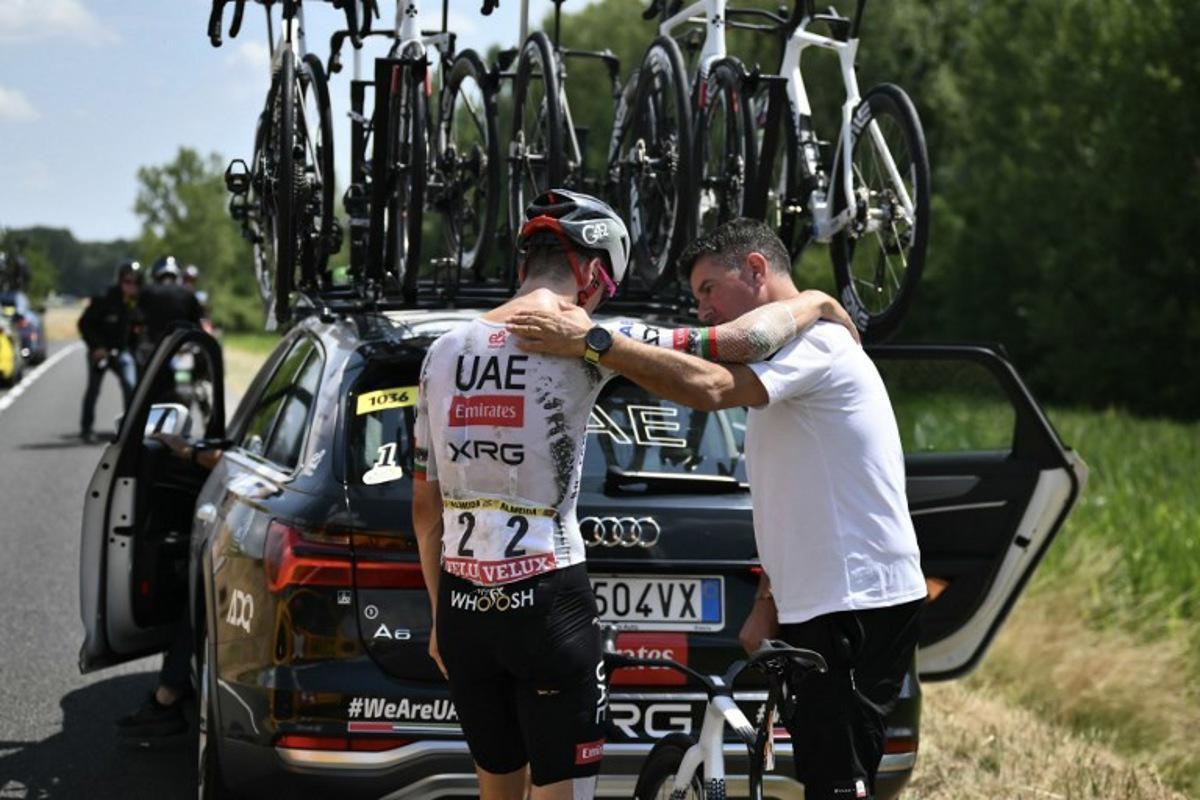 UAE Team Emirates - XRG team's Portuguese rider Joao Almeida is comforted by a team staffed member as he prepared to board his team support vehicle after withdrawing from the race on injury, during the 9th stage of the 112th edition of the Tour de France cycling race, 174.1 km between Chinon and Chateauroux, central France, on July 13, 2025. Marco BERTORELLO / AFP