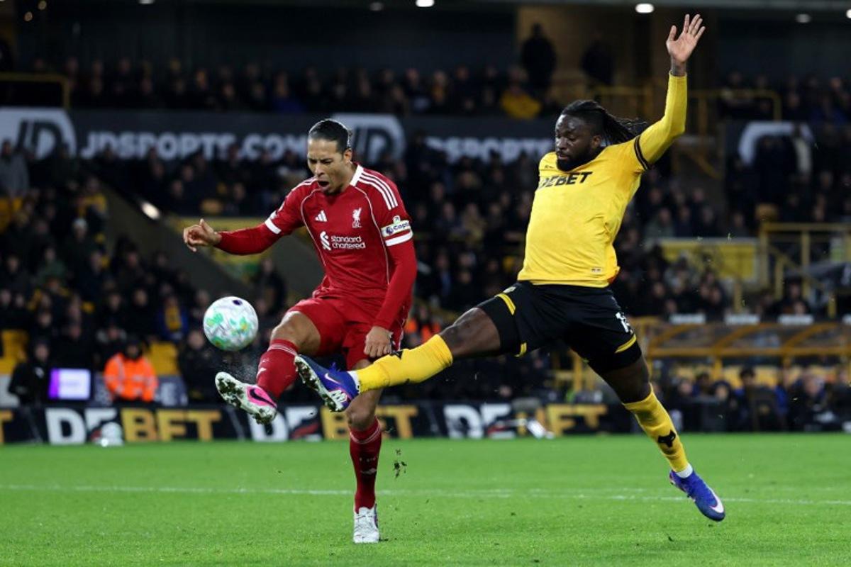 Liverpool's Dutch defender #04 Virgil van Dijk battles for possession with Wolverhampton Wanderers' Nigerian striker #14 Tolu Arokodare during the English Premier League football match between Wolverhampton Wanderers and Liverpool at the Molineux stadium in Wolverhampton, central England on March 3, 2026. Darren Staples / AFP