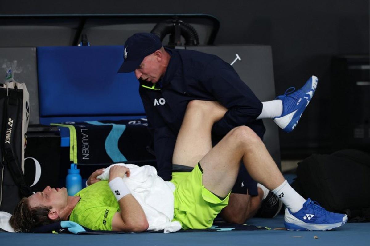 A physio attends to Belgium's Zizou Bergs between points against Poland's Hubert Hurkacz during their men's singles match on day three of the Australian Open tennis tournament in Melbourne on January 20, 2026. IZHAR KHAN / AFP