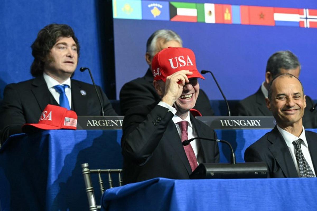FIFA President Gianni Infantino puts on a "USA" hat as he attends the inaugural meeting of the "Board of Peace" hosted by US President Donald Trump at the US Institute of Peace in Washington, DC, on February 19, 2026. President Trump on Thursday gathers allies to inaugurate the "Board of Peace," his new institution focused on progress on Gaza but whose ambitions reach much further. Around two dozen world leaders or other senior officials have come to Washington for the meeting -- including several of Trump's authoritarian-leaning friends and virtually none of the European democrats that traditionally sign on to US initiatives. SAUL LOEB / AFP