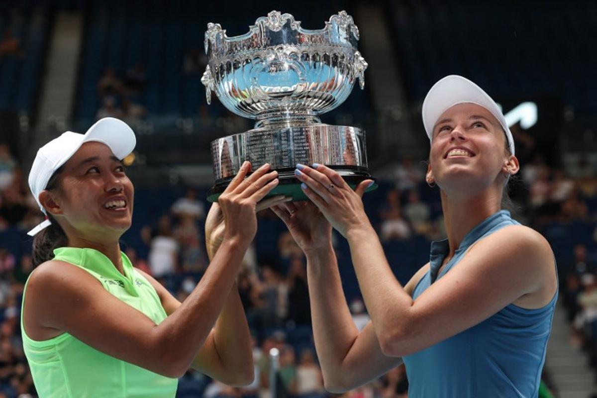 Belgium's Elise Mertens (R) and partner China's Zhang Shuai hold their trophy after winning their women's doubles final match against Kazakhstan's Anna Danilina and Serbia's Aleksandra Krunic on day fourteen of the Australian Open tennis tournament in Melbourne on January 31, 2026. DAVID GRAY / AFP