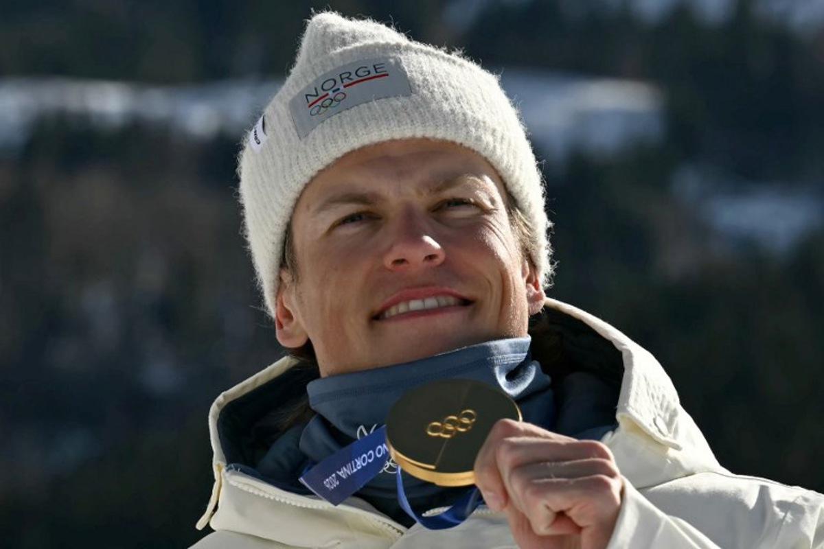 Gold medallist Norway's Johannes Hoesflot Klaebo celebrates on the podium for the men's team cross country free sprint final event of the Milano Cortina 2026 Winter Olympic Games at Tesero Cross-Country Skiing Stadium in Lago di Tesero (Val di Fiemme), on February 18, 2026. Javier SORIANO / AFP