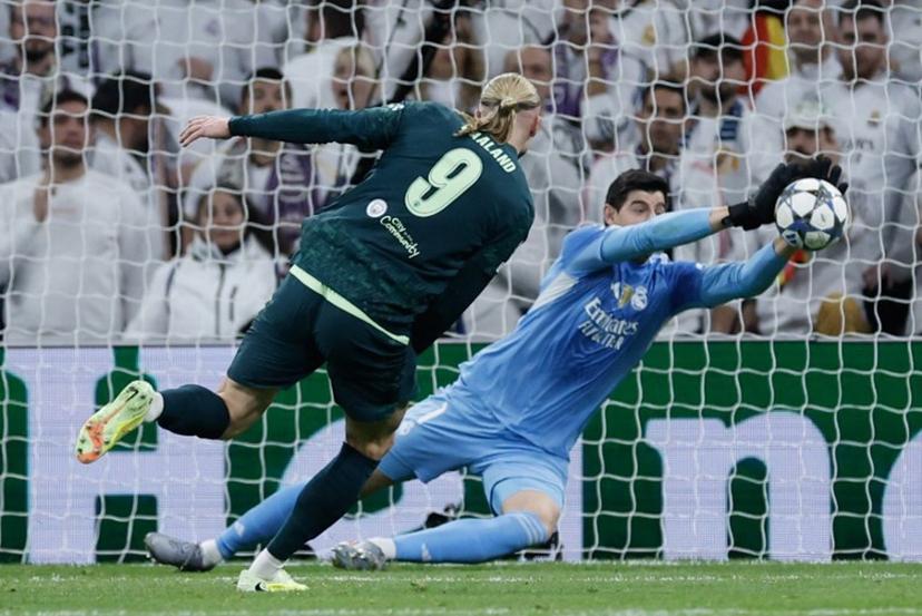 Real Madrid's Belgian goalkeeper #01 Thibaut Courtois (R) makes a save from a shot on goal by Manchester City's Norwegian forward #09 Erling Braut Haland during the UEFA Champions League league phase day 6 football match between Real Madrid CF and Manchester City at Santiago Bernabeu Stadium in Madrid on December 10, 2025. Oscar DEL POZO / AFP