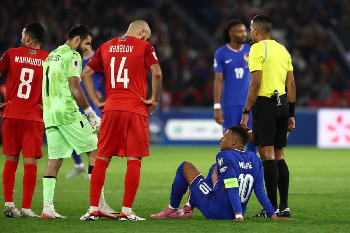 France's forward #10 Kylian Mbappe (2R) talks with Azerbaijan's defender #14 Elvin Badalov (C) and Azerbaijan's goalkeeper #01 Shakhrudin Magomedaliyev (2L) as he sits on the pitch during the FIFA World Cup 2026 Group D European qualification football match between France and Azerbaijan at the Parc des Princes Stadium in Paris, on October 10, 2025. FRANCK FIFE / AFP
