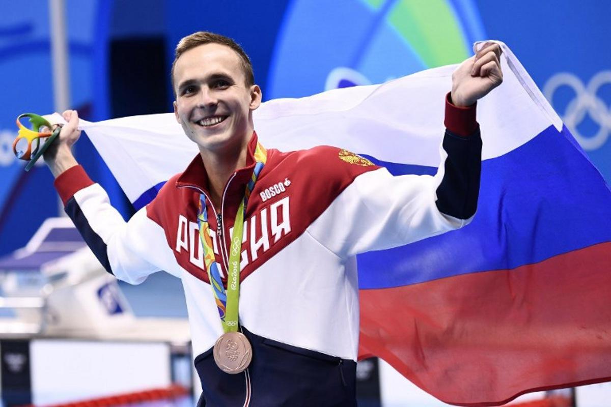 Russia's Anton Chupkov waves his national flag after he won the bronze medal in the Men's 200m Breaststroke Final during the swimming event at the Rio 2016 Olympic Games at the Olympic Aquatics Stadium in Rio de Janeiro on August 10, 2016. CHRISTOPHE SIMON / AFP