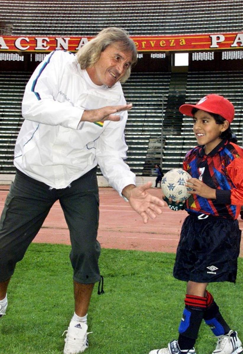 (FILES) Argentinian goalkeeper Hugo Orlando Gatti (L) jokes with a child on January 22, 2004 at the Hernando Siles stadium in La Paz, Bolivia. The so-called 'El Loco' Gatti, emblematic goalkeeper of Argentine football and former member of the national team, died on April 20, 2025 at the age of 80, according to CONMEBOL sources. Gatti had been in hospital in Buenos Aires for two months with a hip fracture, but his health had deteriorated due to pneumonia. Aizar RALDES / AFP