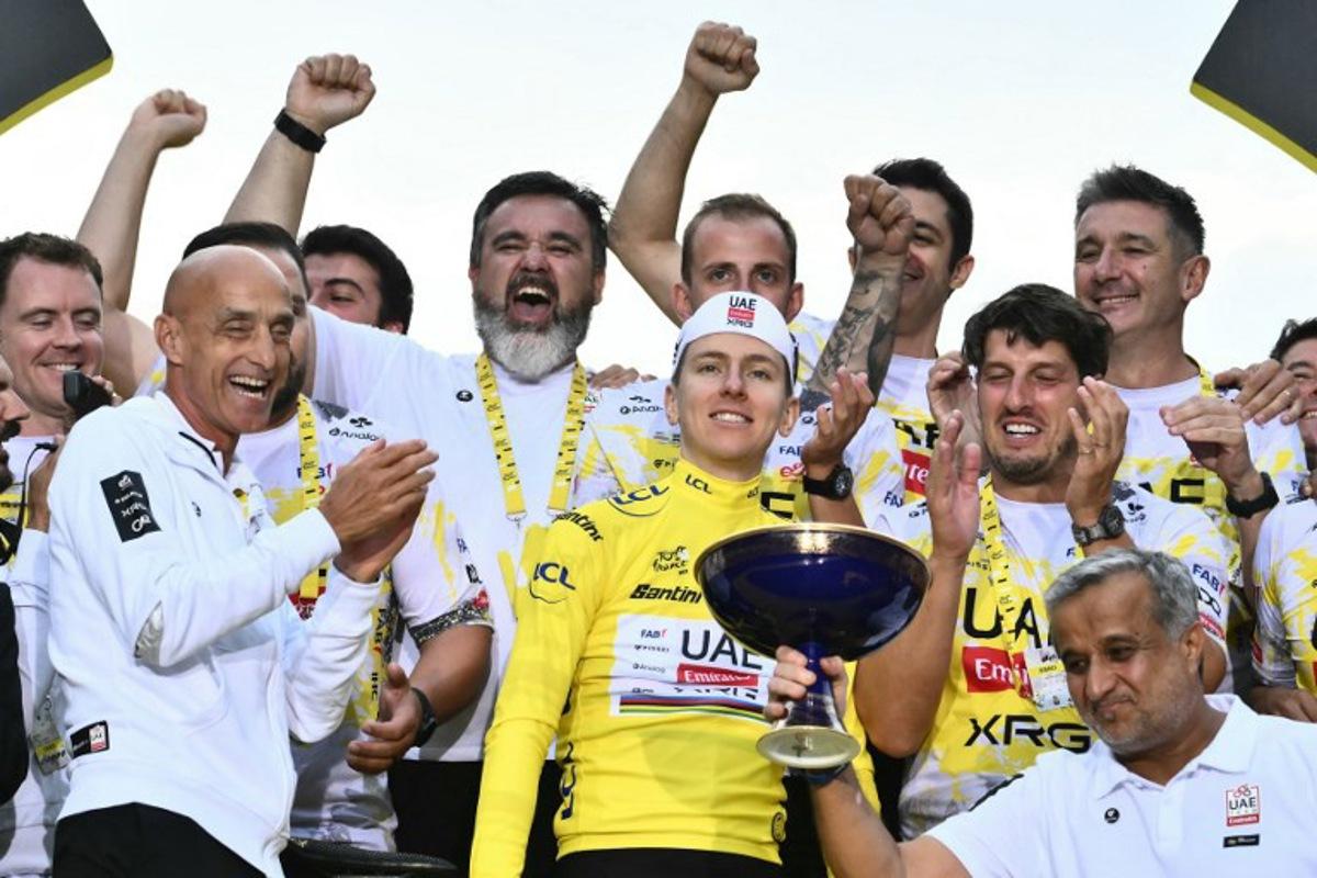 UAE Team Emirates - XRG team's Slovenian rider Tadej Pogacar wearing the overall leader's yellow jersey celebrates his overall victory with team staff after the 21st and final stage of the 112th edition of the Tour de France cycling race, 132.3 km between Mantes-la-Ville and Paris Champs-Élysees, on July 27, 2025. Marco BERTORELLO / AFP