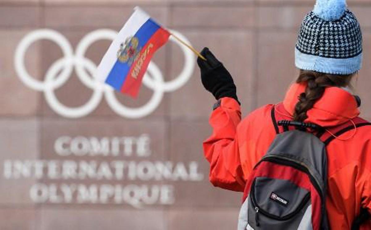 A supporter waves a Russian flag in front of the logo of the International Olympic Committee (IOC) at their headquarters on December 5, 2017 in Pully near Lausanne. The International Olympic Committee meets to decide whether to bar Russia from the 2018 Winter Olympics for doping violations, in one of the weightiest decisions ever faced by the Olympic movement. Fabrice COFFRINI / AFP