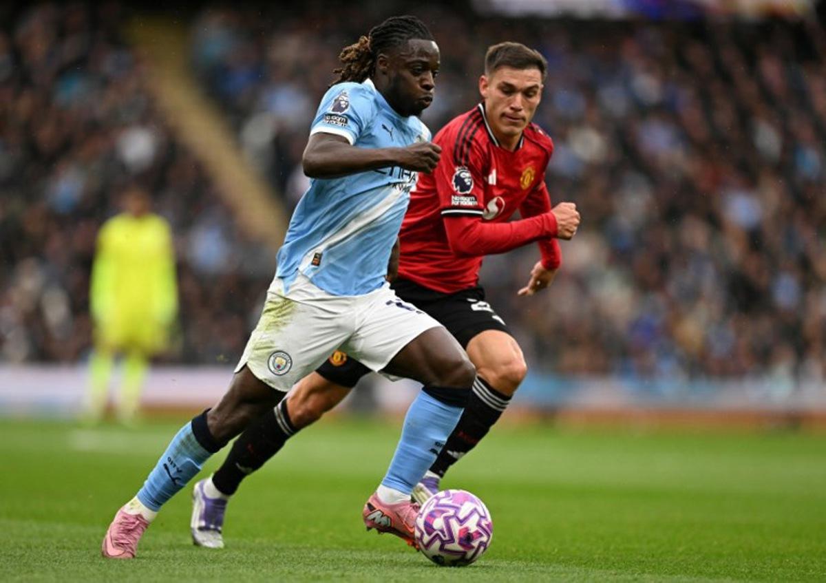 Manchester City's Belgian midfielder #11 Jeremy Doku (L) runs with the ball shadowed by Manchester United's Uruguayan midfielder #25 Manuel Ugarte (R) during the English Premier League football match between Manchester City and Manchester United at the Etihad Stadium in Manchester, north west England, on September 14, 2025. Oli SCARFF / AFP