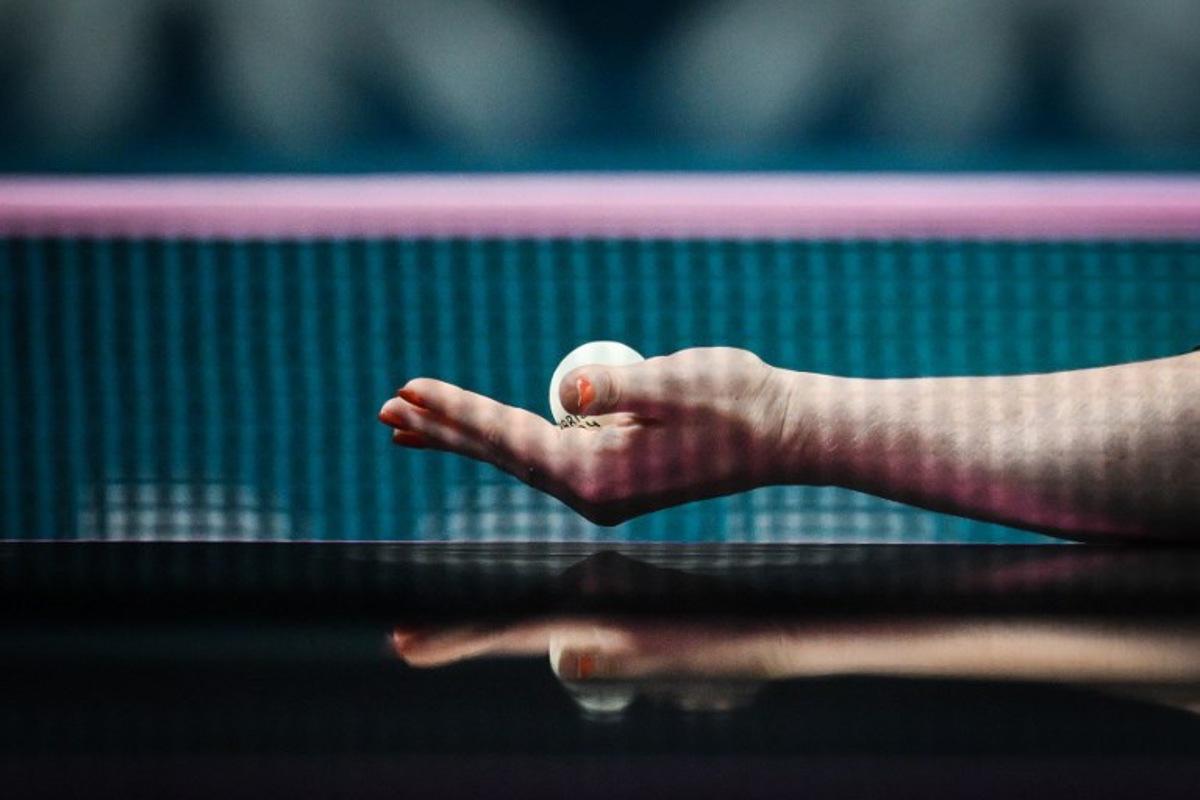 The reflection of the arm and hand of Netherlands' Britt Eerland is pictured on the table tennis table as she serves the ball to Czech Republic's Hana Matelova during their women's table tennis singles round of 32 at the Paris 2024 Olympic Games at the South Paris Arena in Paris on July 29, 2024. JUNG Yeon-je / AFP