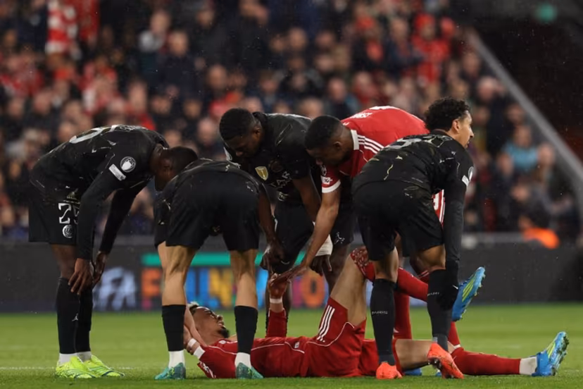 Players care for Liverpool's French striker #22 Hugo Ekitike who lies injured during the UEFA Champions League quarter final, second-leg football match between Liverpool and Paris Saint-Germain at Anfield in Liverpool, north west England on April 14, 2026. FRANCK FIFE / AFP