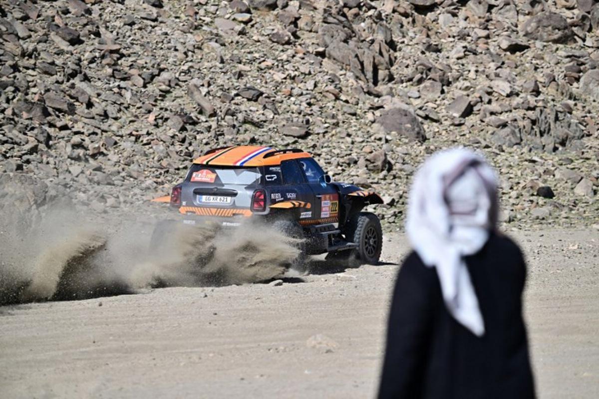 A local watches X-Raid Team Belgian driver Guillaume de Mevius and French co-driver Mathieu Baumel compete in the prologue, which determines the starting line-up for the first stage of the 48th edition of the Dakar Rally 2026, between Yanbu and Yanbu, Saudi Arabia, on January 3, 2026. Giuseppe CACACE / AFP