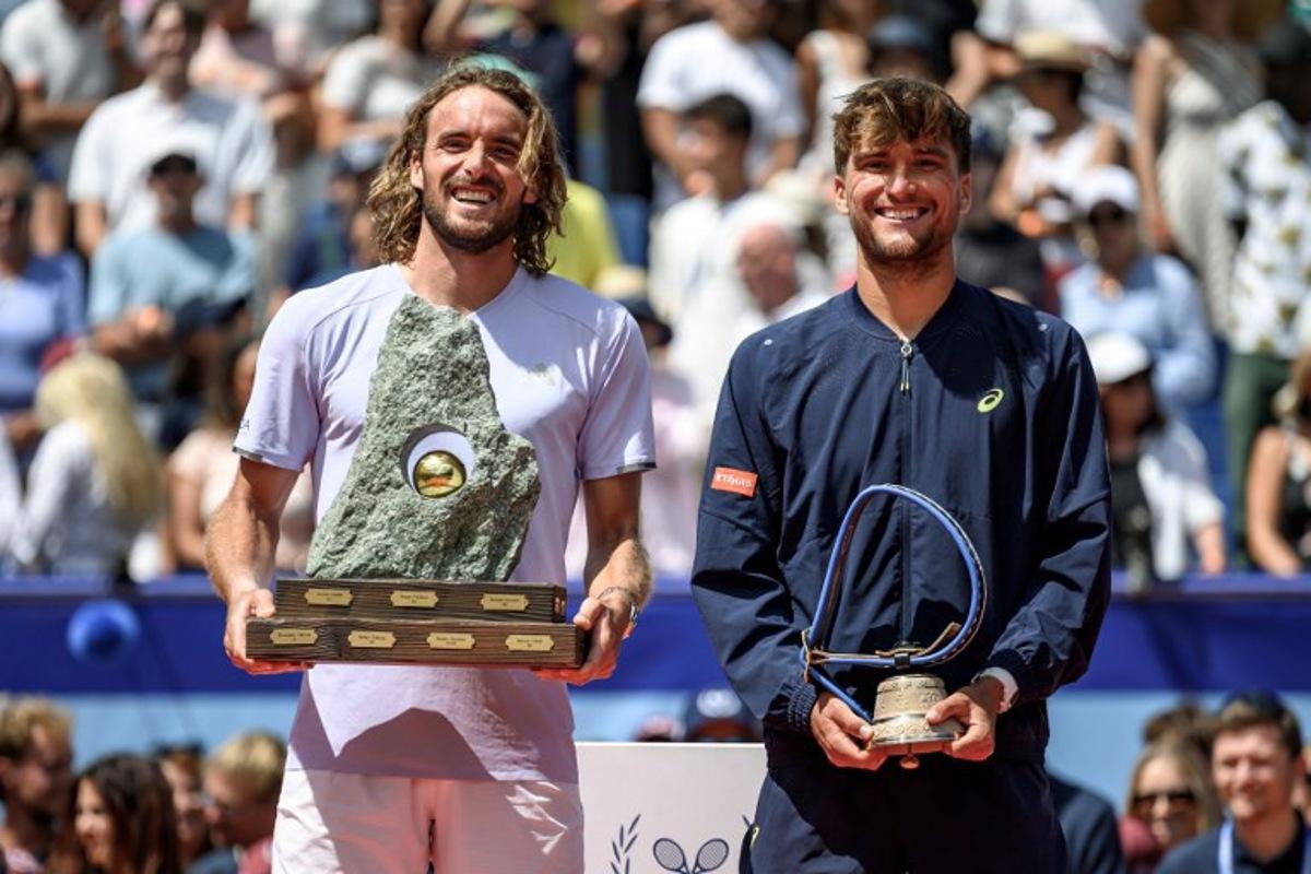 Greece's Stefanos Tsitsipas (L) poses with the trophy following his victory against Belgium's Raphael Collignon (R) during their men's singles final match at the Swiss Open tennis tournament in Gstaad, on July 19, 2026. Fabrice COFFRINI / AFP