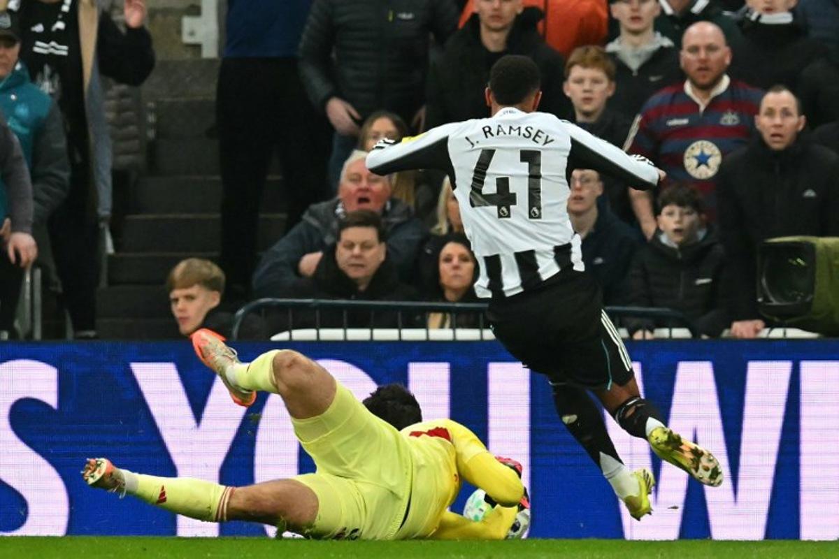 Newcastle United's English midfielder #41 Jacob Ramsey goes down after Manchester United's Belgian goalkeeper #31 Senne Lammens takes the ball from him, he was subsequently sent off for a second yellow card for simulation during the English Premier League football match between Newcastle United and Manchester United at St James' Park in Newcastle-upon-Tyne, north east England on March 4, 2026. ANDY BUCHANAN / AFP