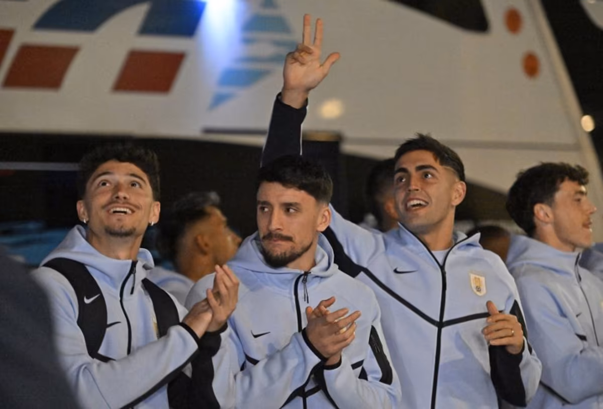 (L to R) Uruguay's midfielder #15 Emiliano Martinez, Uruguay's defender #22 Joaquin Piquerez and Uruguay's goalkeeper #12 Santiago Mele acknowledge fans as the Uruguay national football team arrives at Carrasco International Airport ahead of its departure to Mexico for the FIFA 2026 World Cup football tournament, in Ciudad de la Costa, Canelones department, Uruguay, on June 9, 2026. Santiago Mazzarovich / AFP