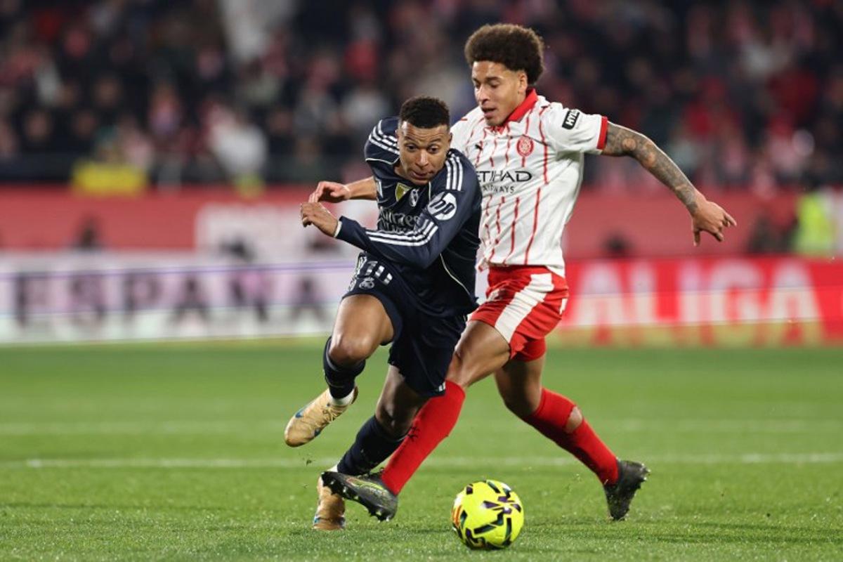 Real Madrid's French forward #10 Kylian Mbappe (L) fights for the ball with Girona's Belgian defender #20 Axel Witsel during the Spanish league football match between Girona FC and Real Madrid CF at Montilivi Stadium in Girona on November 30, 2025. Josep LAGO / AFP